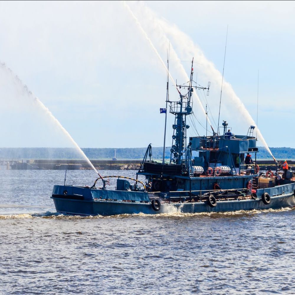 A large blue boat is spraying water on the water