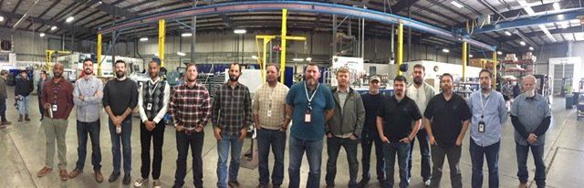 a group of men are posing for a picture in a factory