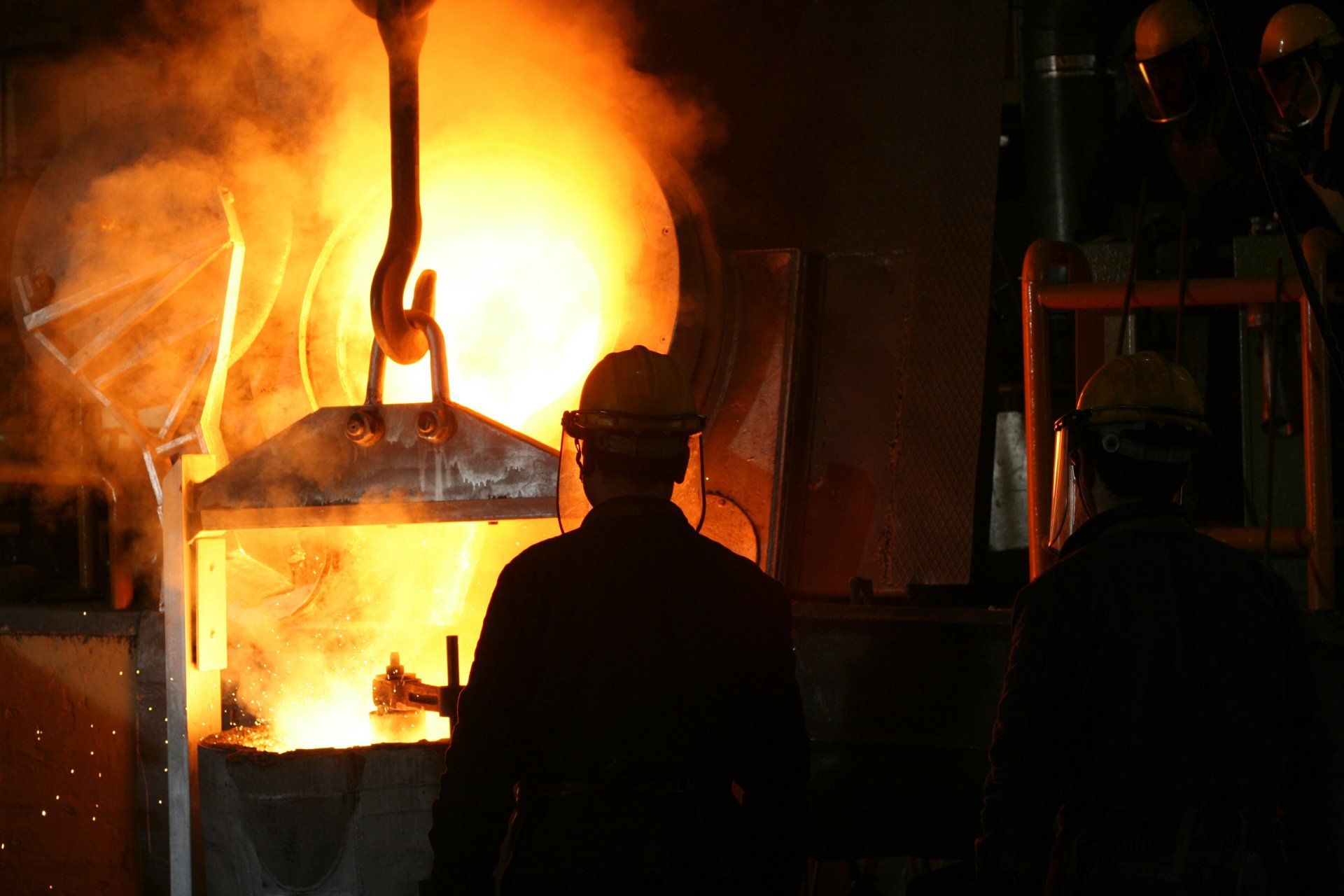 A man is standing in front of a fire in a factory.