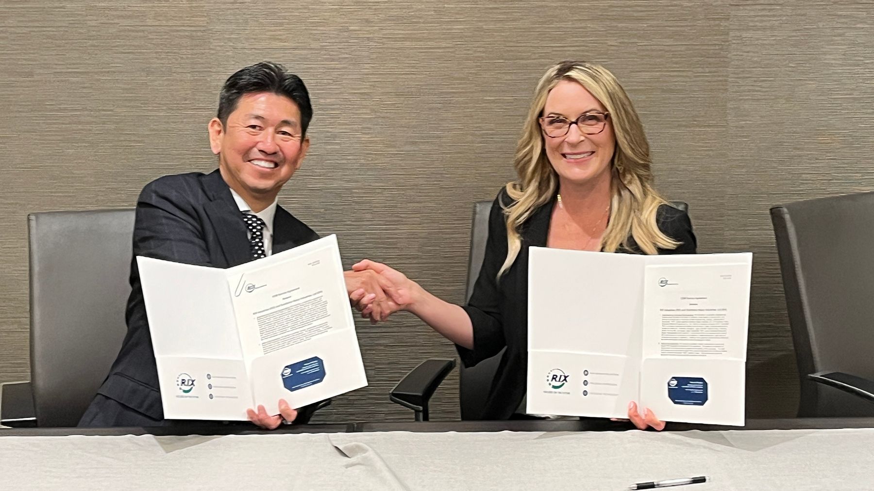Man and Woman holding up signed contracts and shaking hands