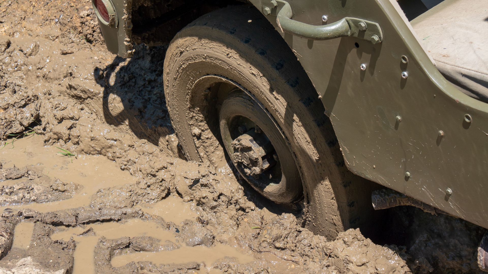 A jeep is stuck in the mud on a muddy road.