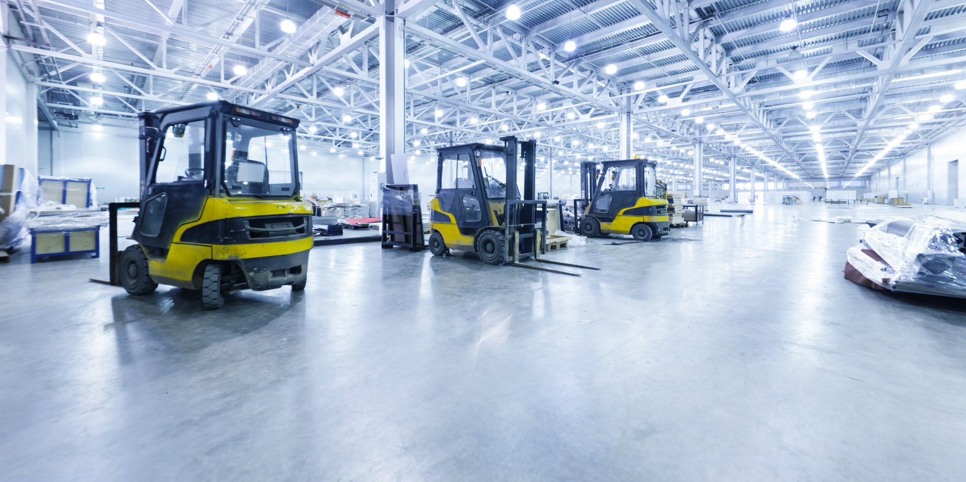 A row of forklifts are parked in a large warehouse.
