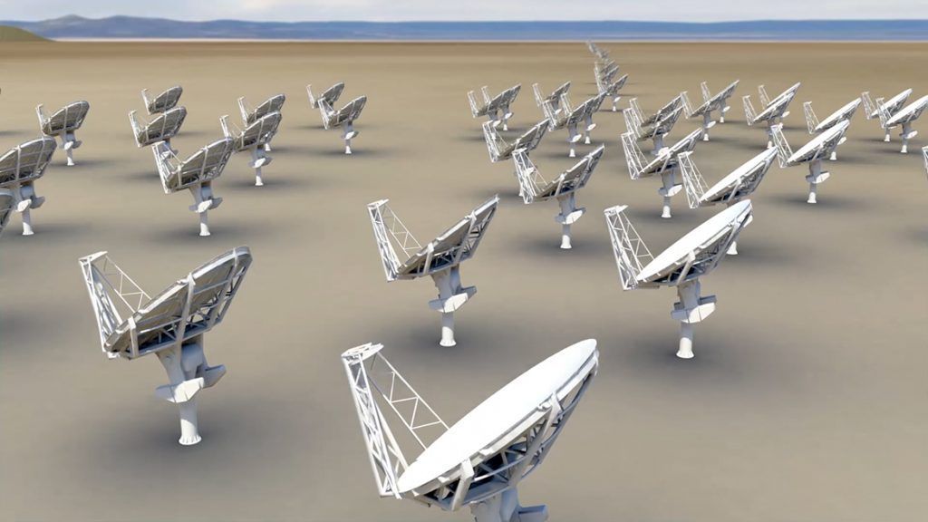 A group of satellite dishes are lined up in a field
