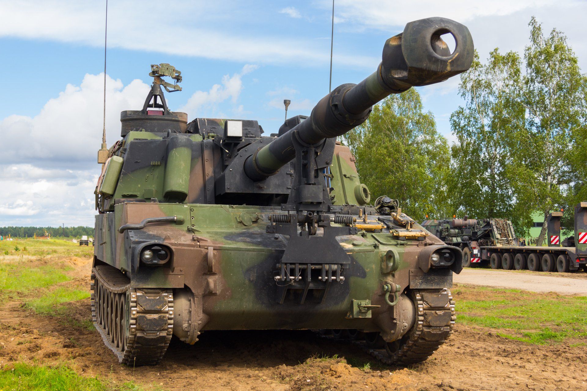 A large military tank is parked in a field.
