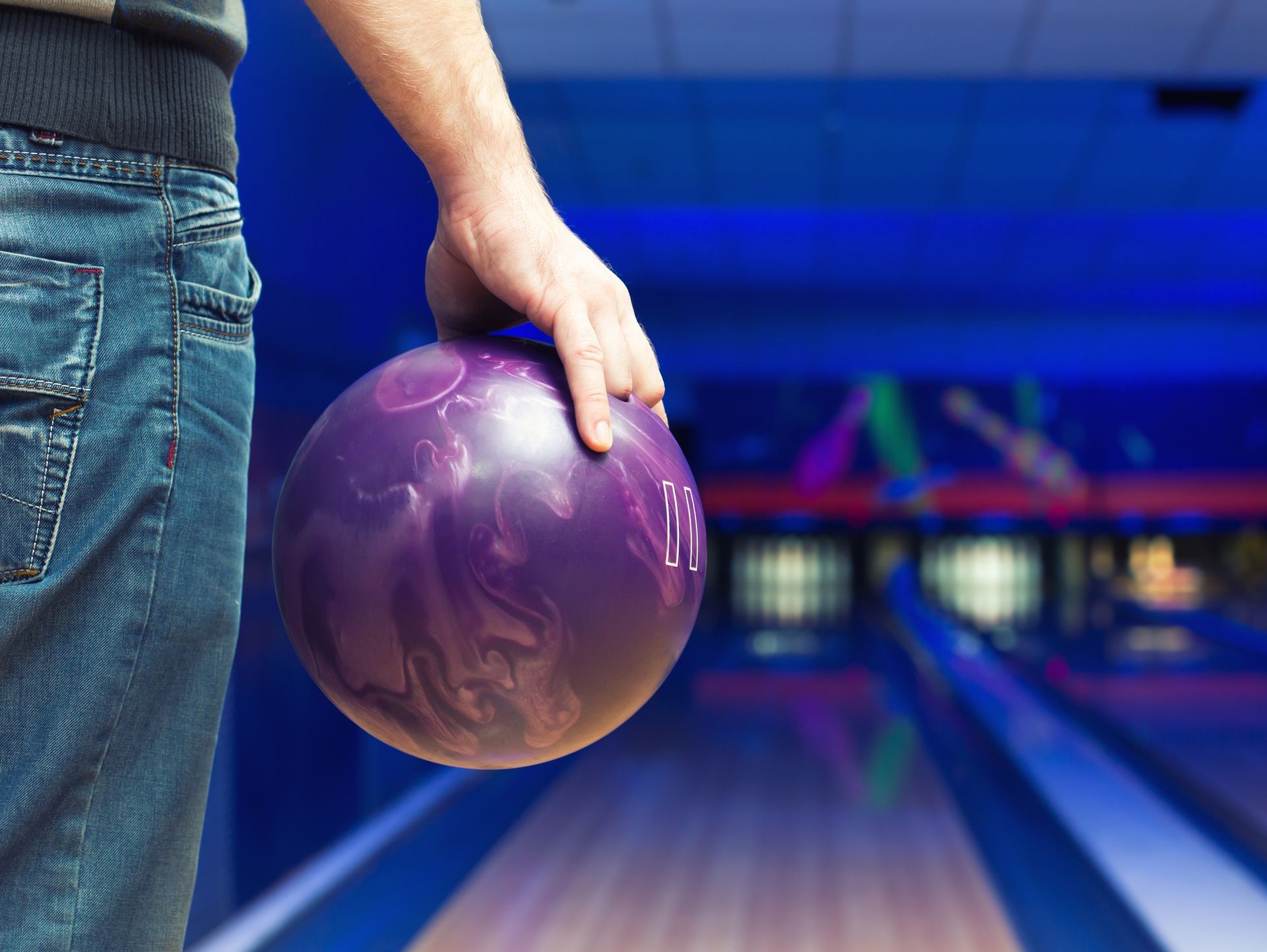 A bowling pin , bowling ball and bowling shoes on a bowling alley.