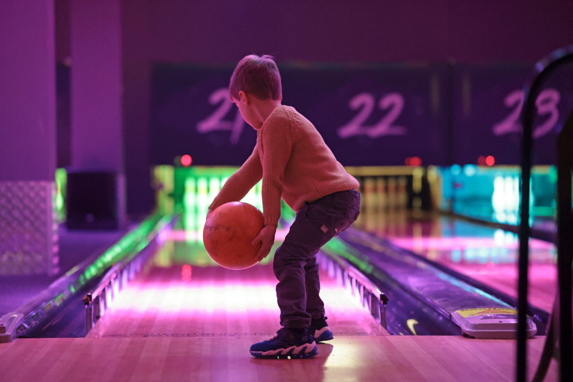 A young boy is playing bowling on a bowling alley. A young boy is playing bowling on a bowling alley.