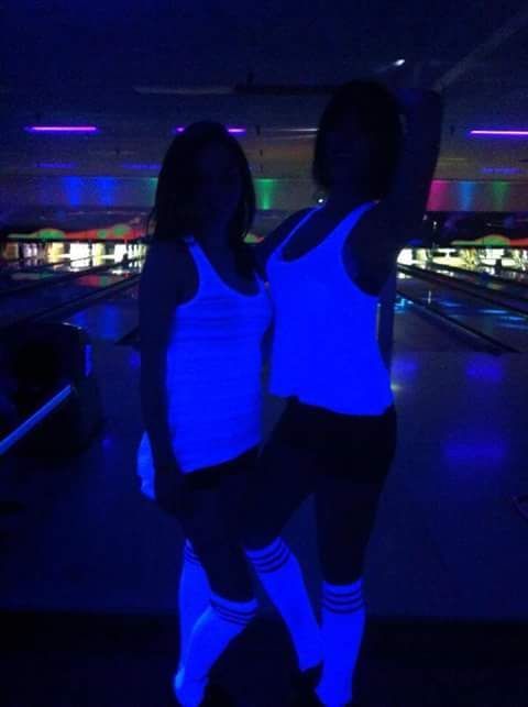A group of people are dancing in a bowling alley.