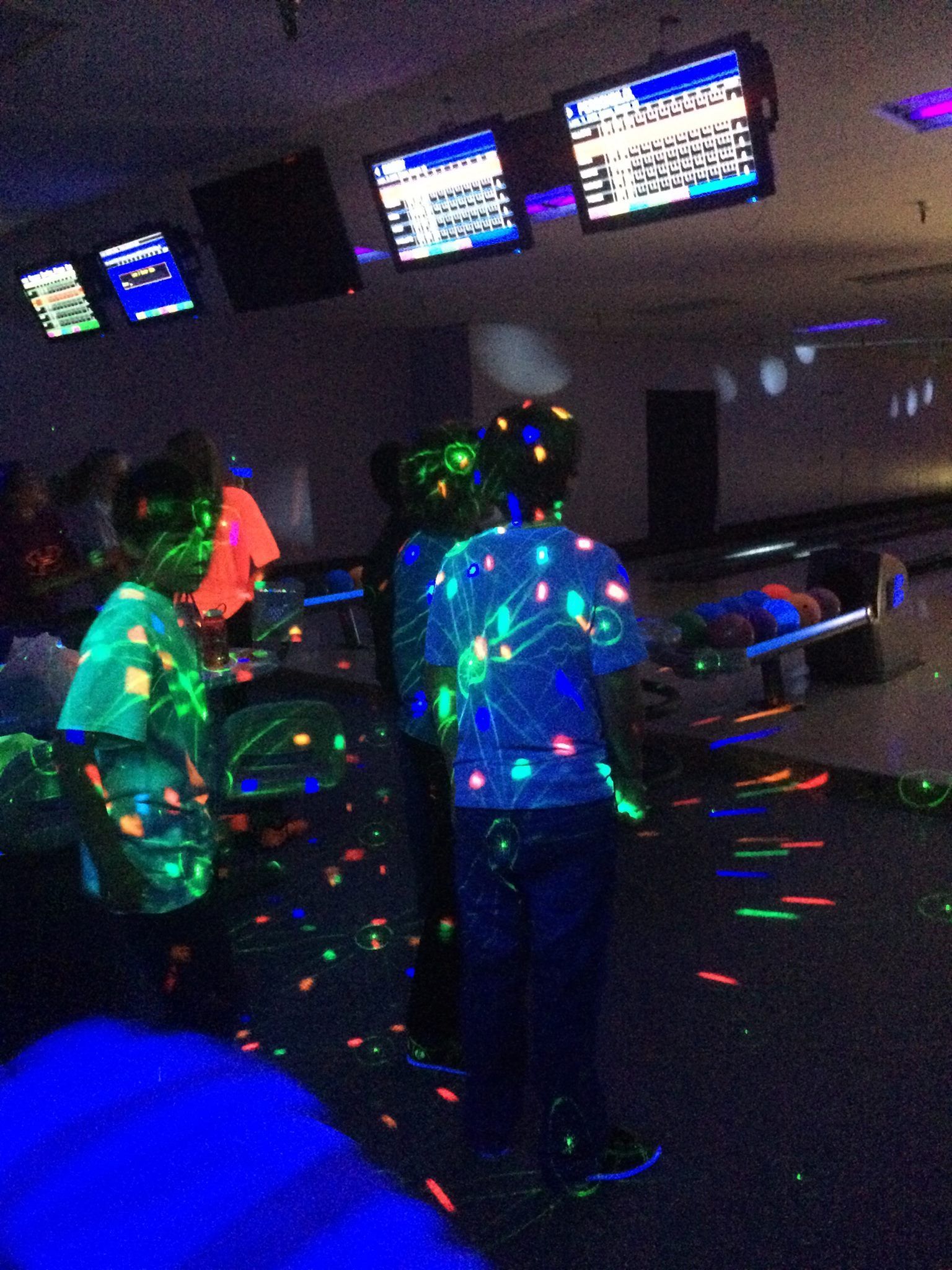 A woman is taking a picture of a family at a bowling alley.