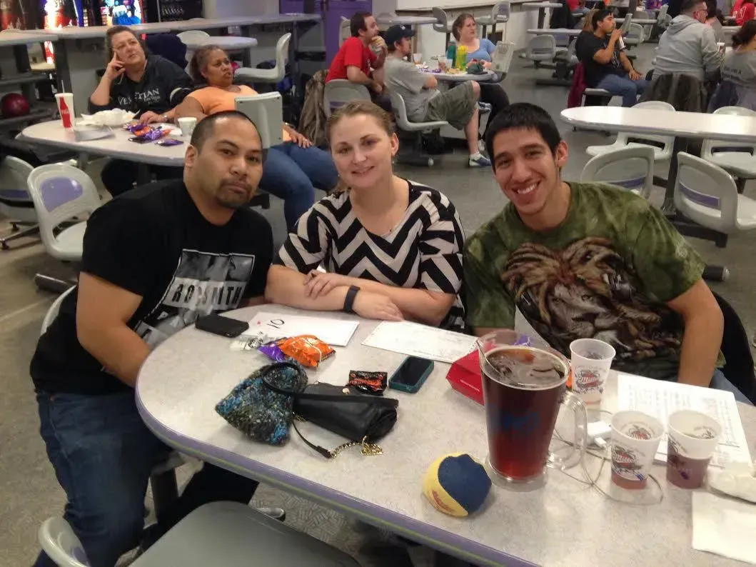Three people are sitting at a table in a bowling alley Three people are sitting at a table in a bowling alley