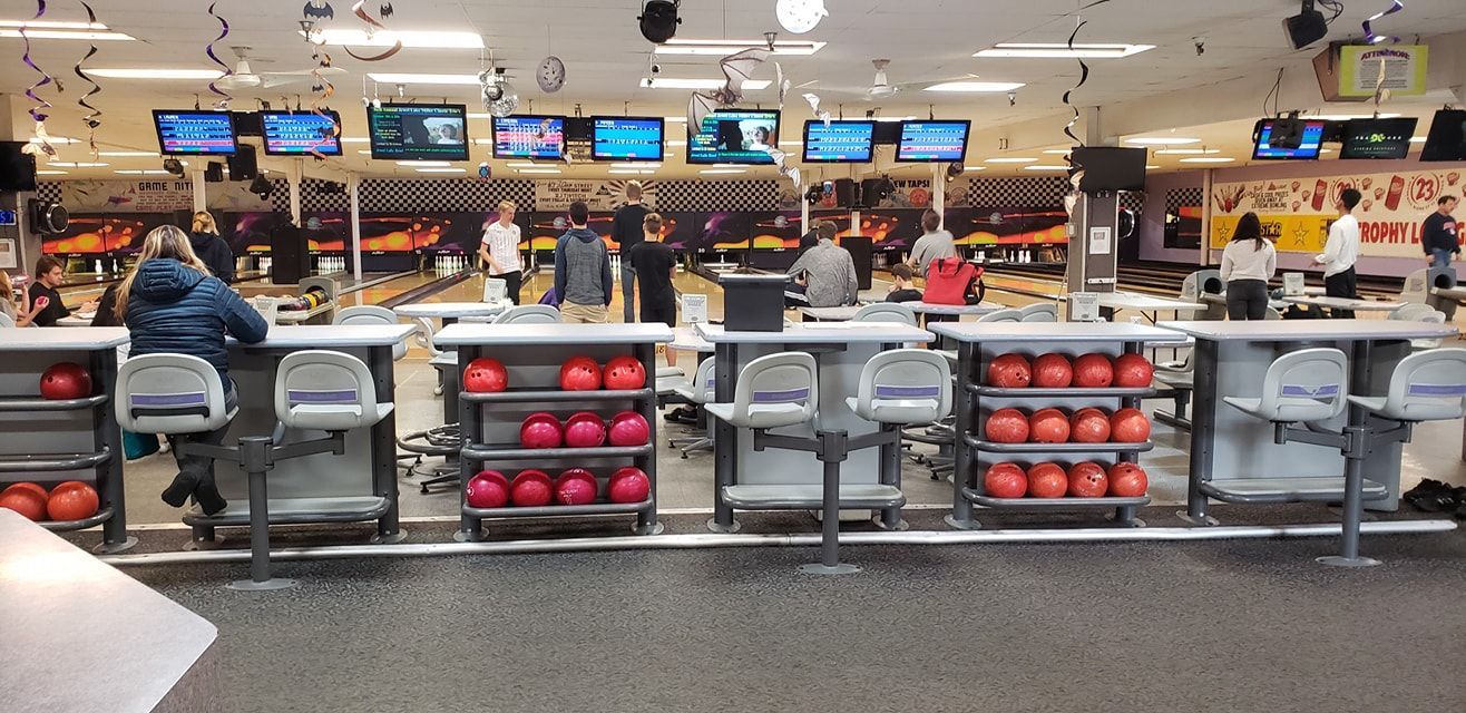 A bunch of bowling balls are lined up in a bowling alley