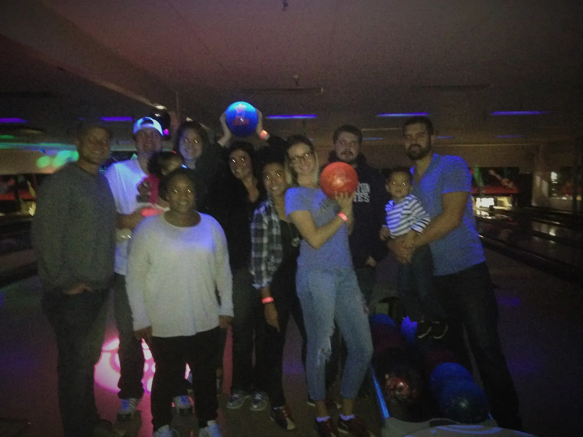 A group of people are posing for a picture at a bowling alley.