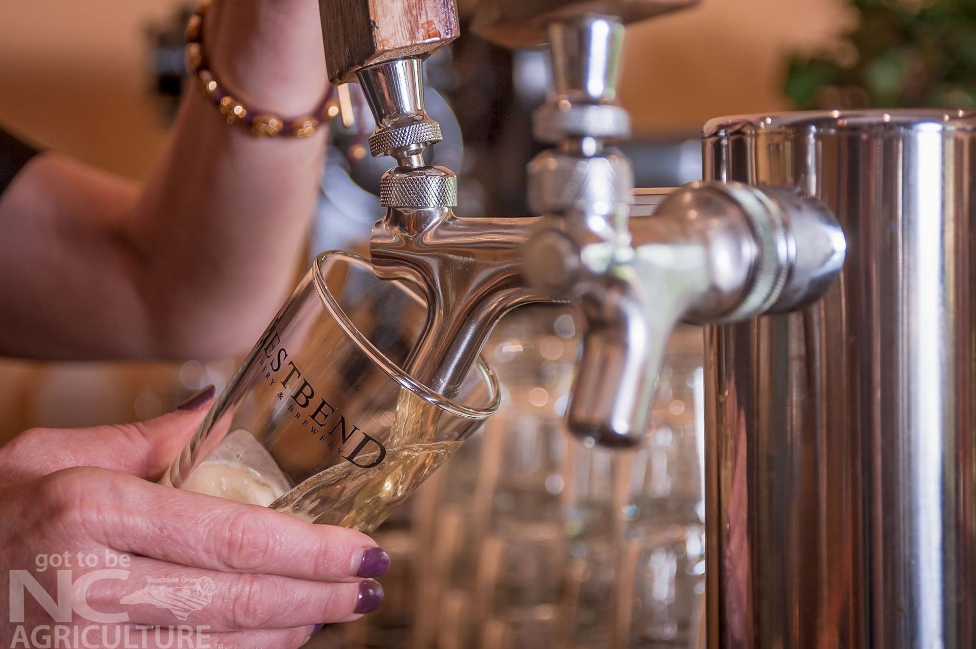 A woman is pouring beer into a glass from a tap.