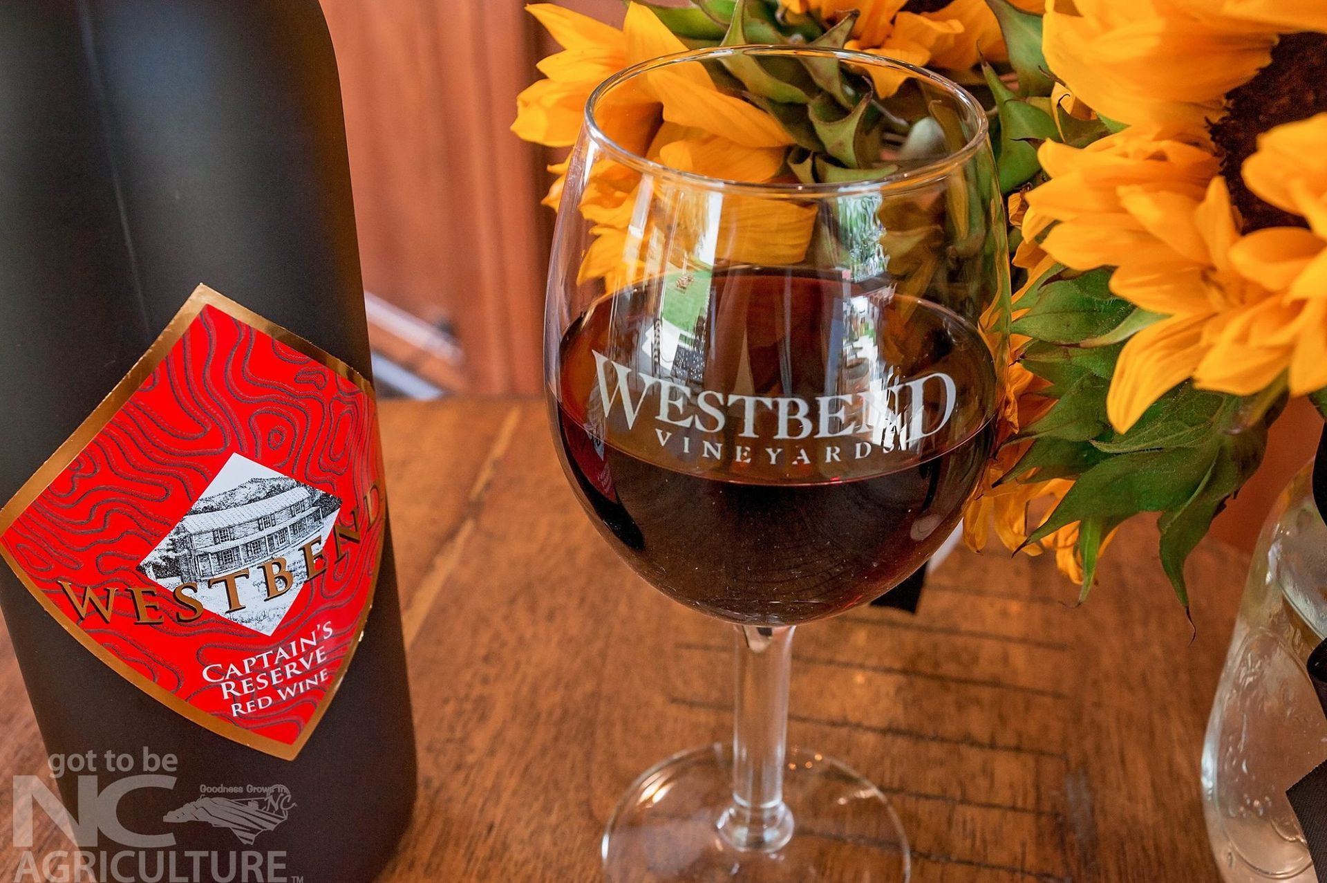 A bottle of westbend wine next to a glass of wine