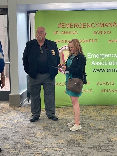 A man and a woman are standing in front of a green backdrop.