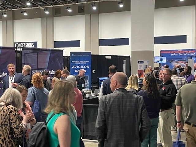 A large group of people are standing in a room at a convention.