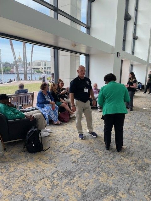 A man and a woman are dancing in a room with people sitting on benches.
