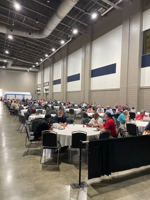 A group of people are sitting at tables in a large room.