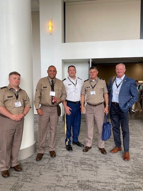 A group of men in military uniforms are standing next to each other in a hallway.