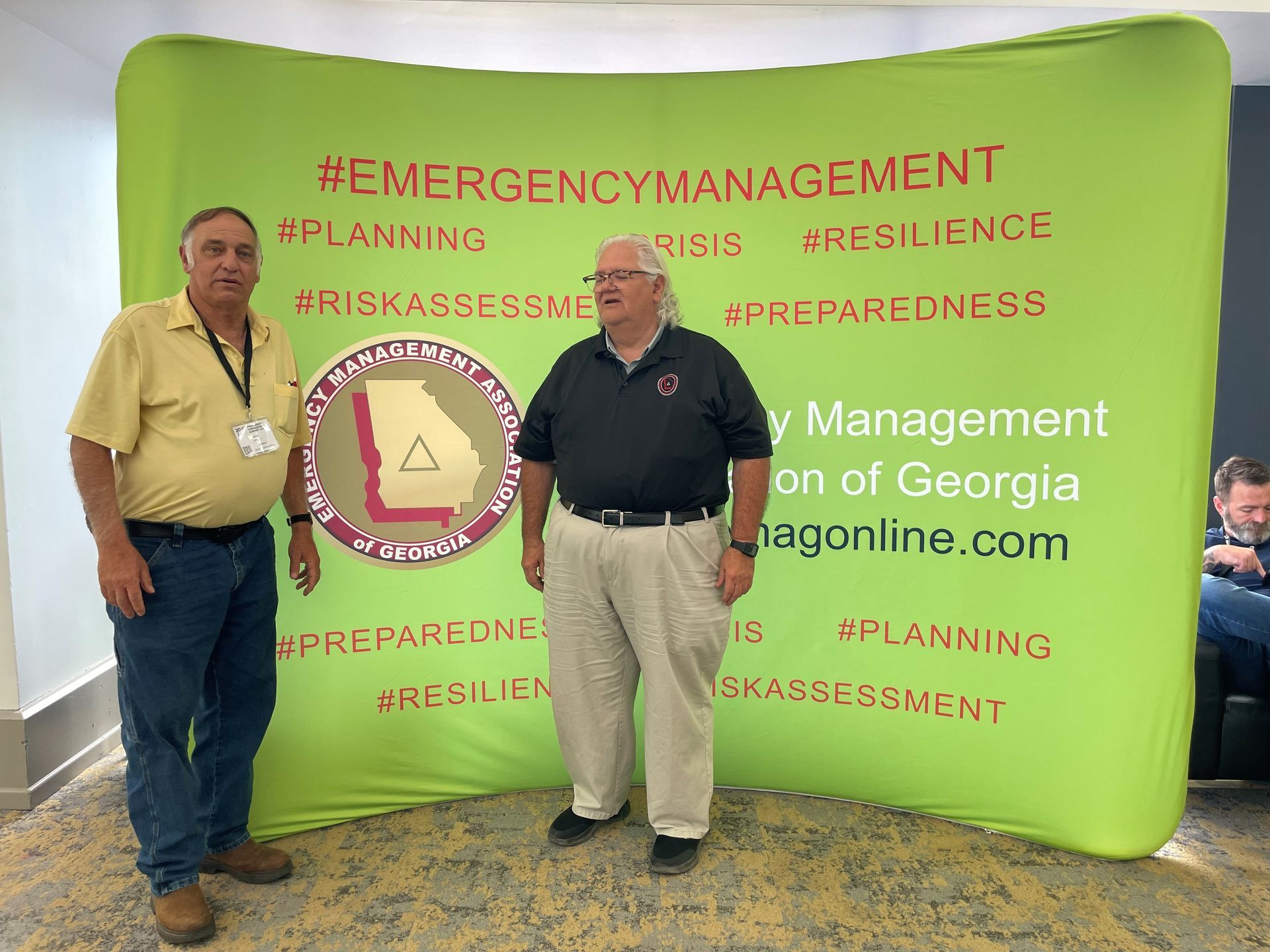 Two men standing in front of a sign that says emergency management