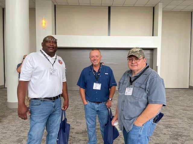Three men standing next to each other in front of a building