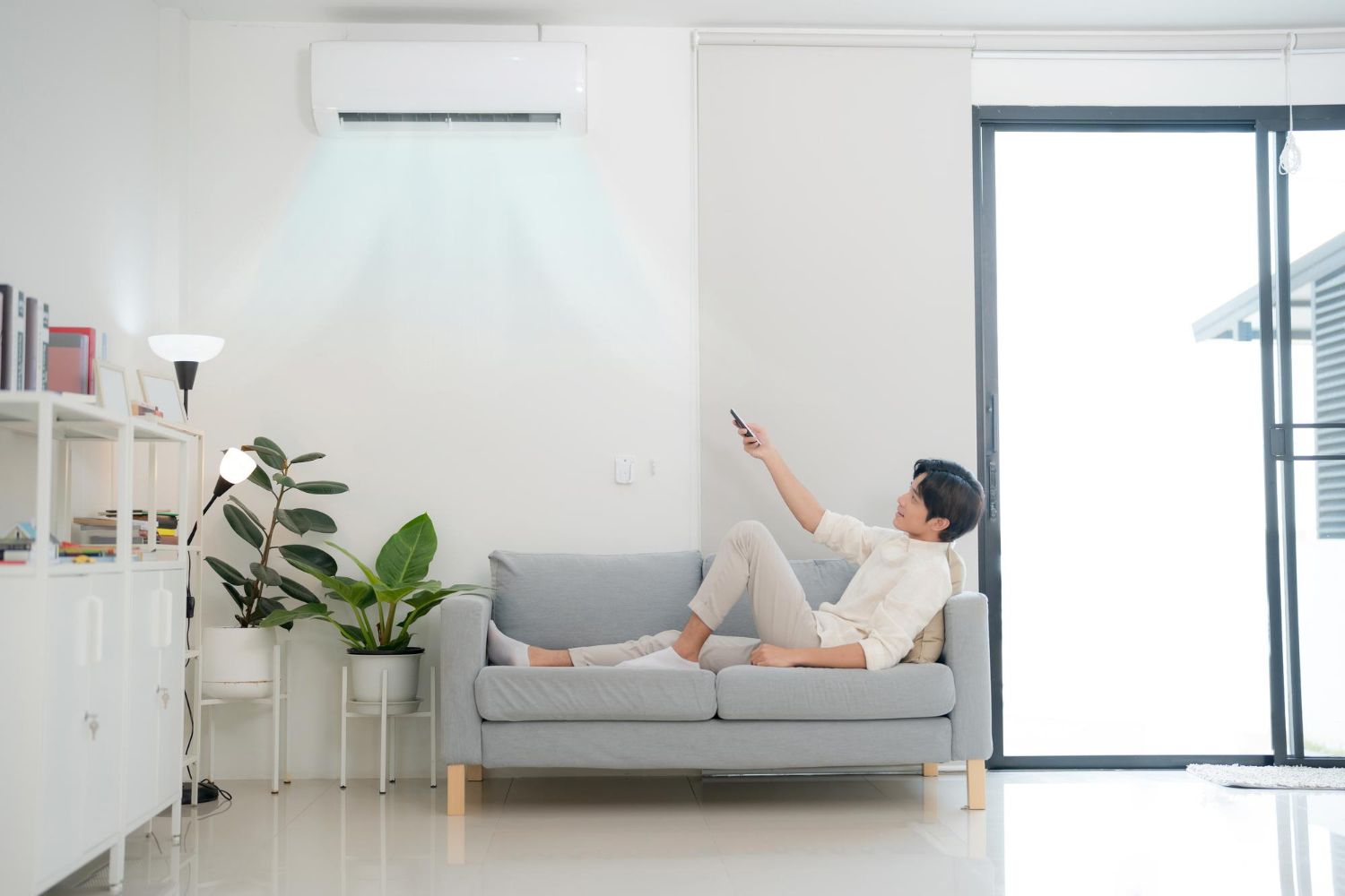A man wearing a hard hat and safety glasses is working on an air conditioner.
