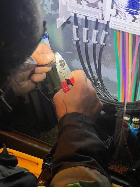 Henkilö katkaisee pihtejä katkaistakseen johdon ohjauspaneelissa, jossa on erivärisiä kaapeleita.