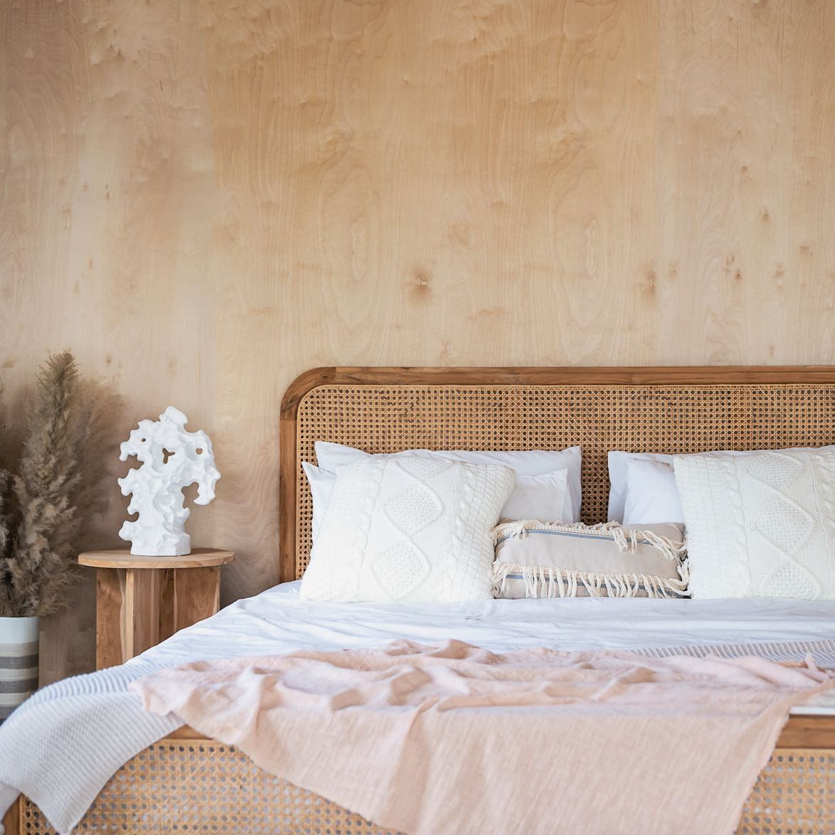 A bed with a wicker headboard and white pillows in a bedroom.