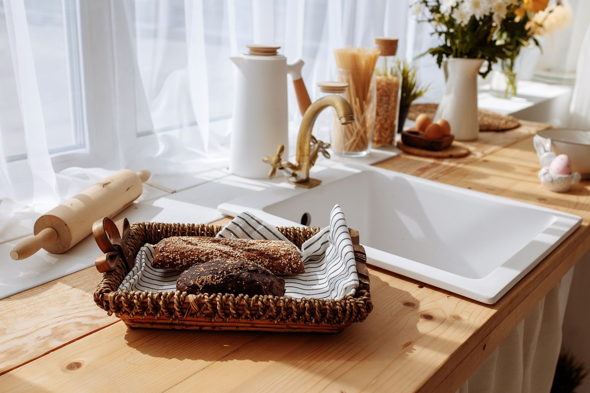 A basket of cookies is sitting on a wooden counter next to a kitchen sink.