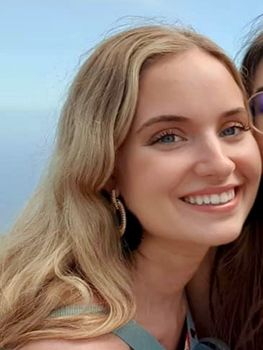 A close up of a woman wearing sunglasses and smiling.