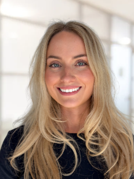 A close up of a woman wearing sunglasses and smiling.