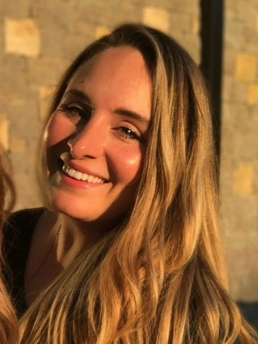 A woman with long blonde hair is smiling for the camera