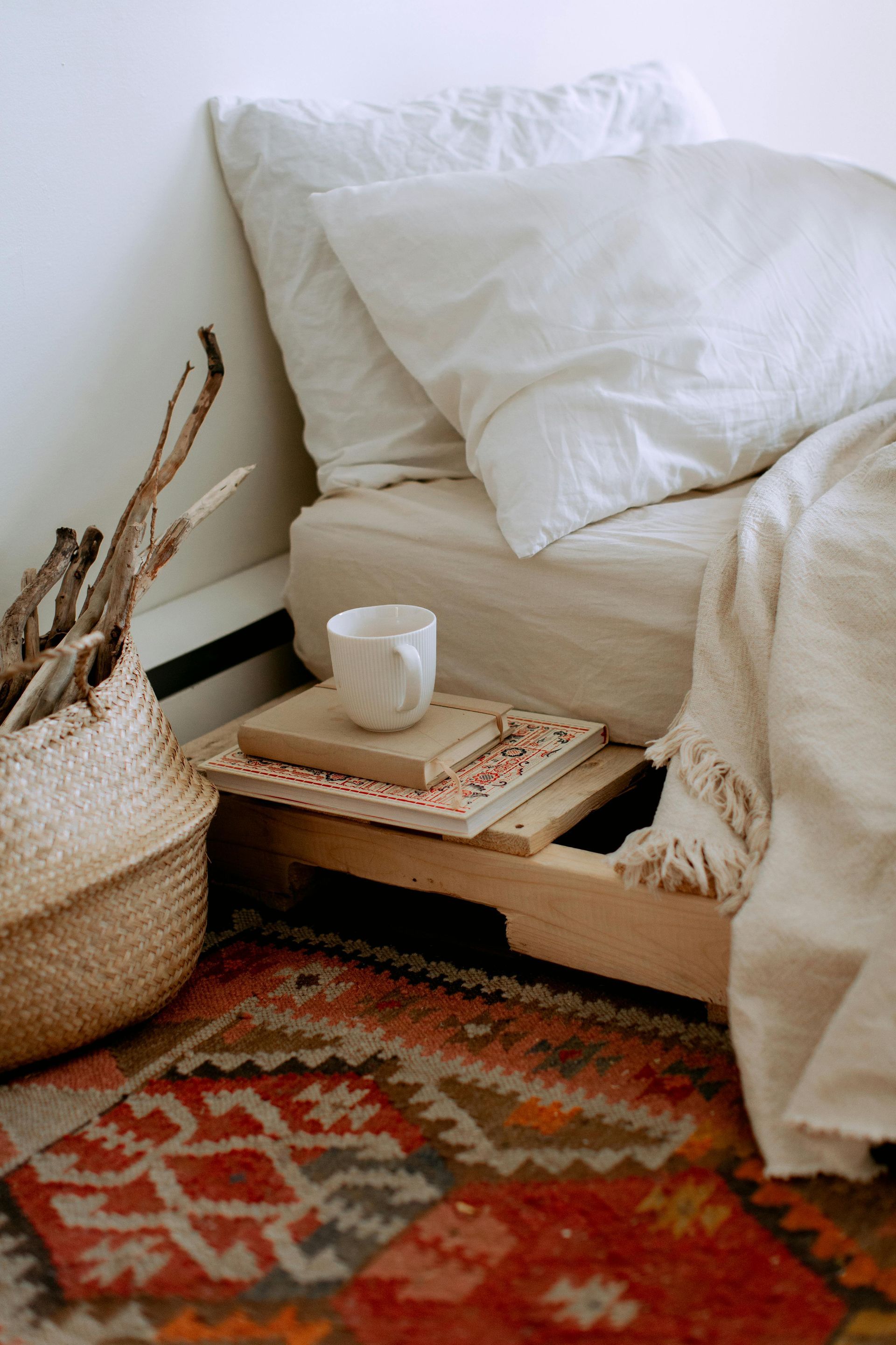 There is a bed with a nightstand underneath it and a rug.