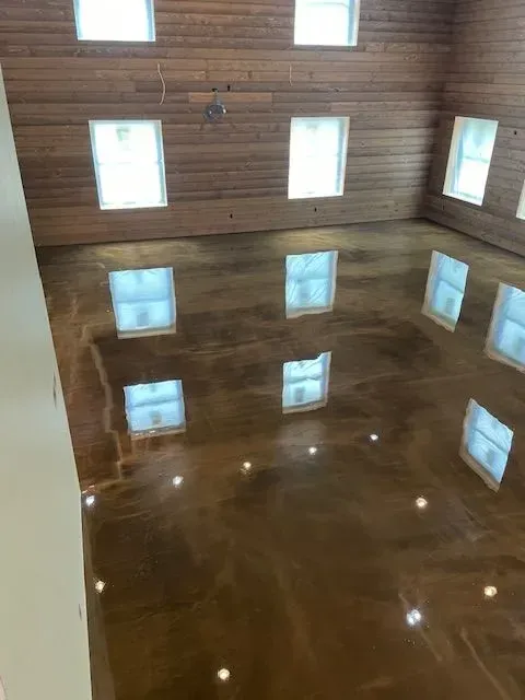 Shiny brown metallic epoxy floor reflects windows and ceiling in a room.