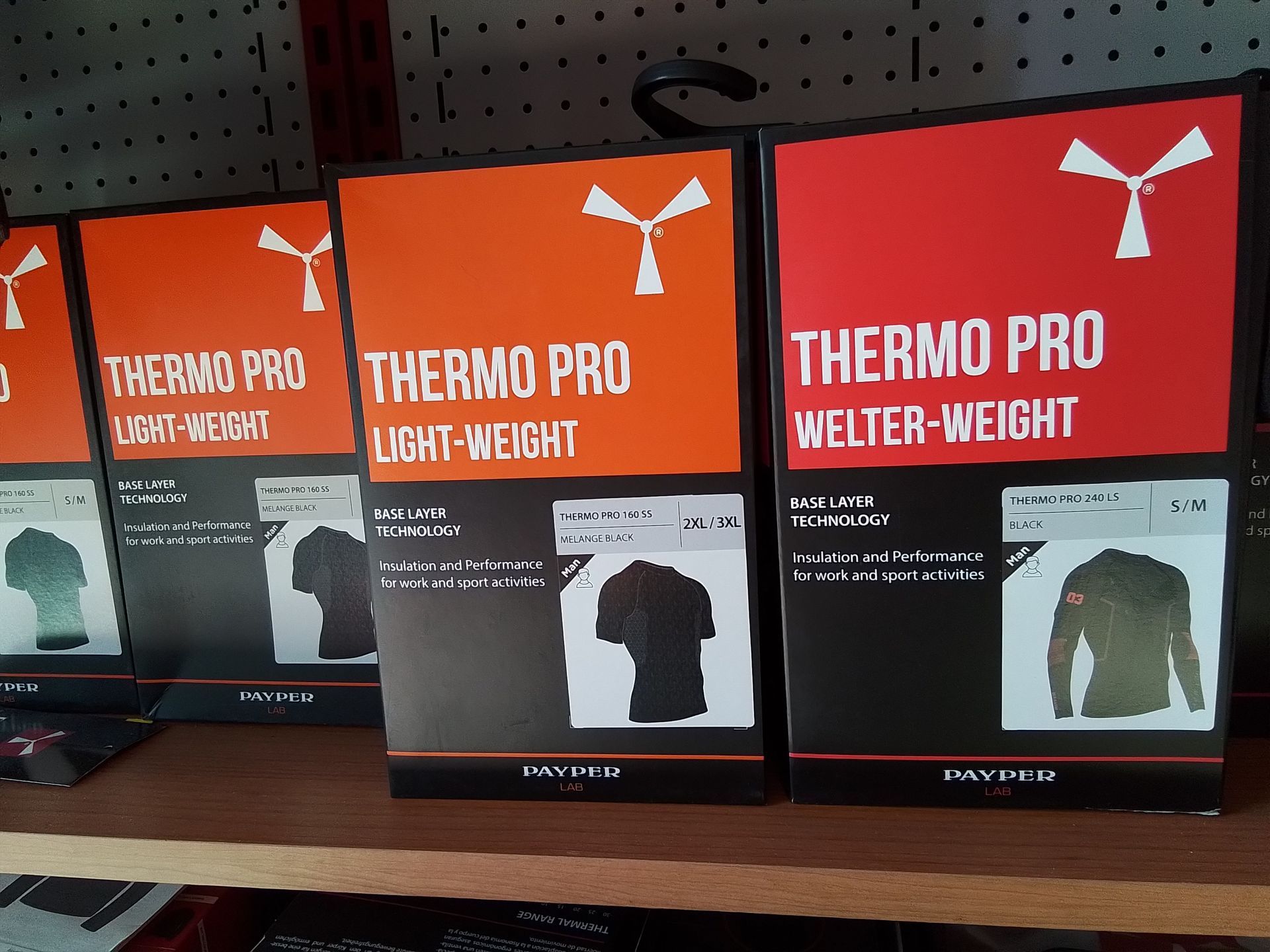 Scatole di indumenti Thermo Pro, arancioni e rossi, in mostra, con il logo di un mulino a vento.