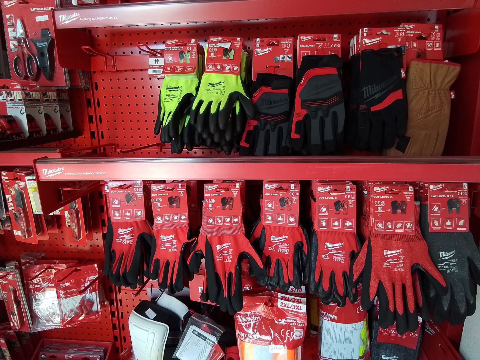 Esposizione di guanti da lavoro rossi e neri in un negozio al dettaglio, con alcuni guanti di un verde brillante.