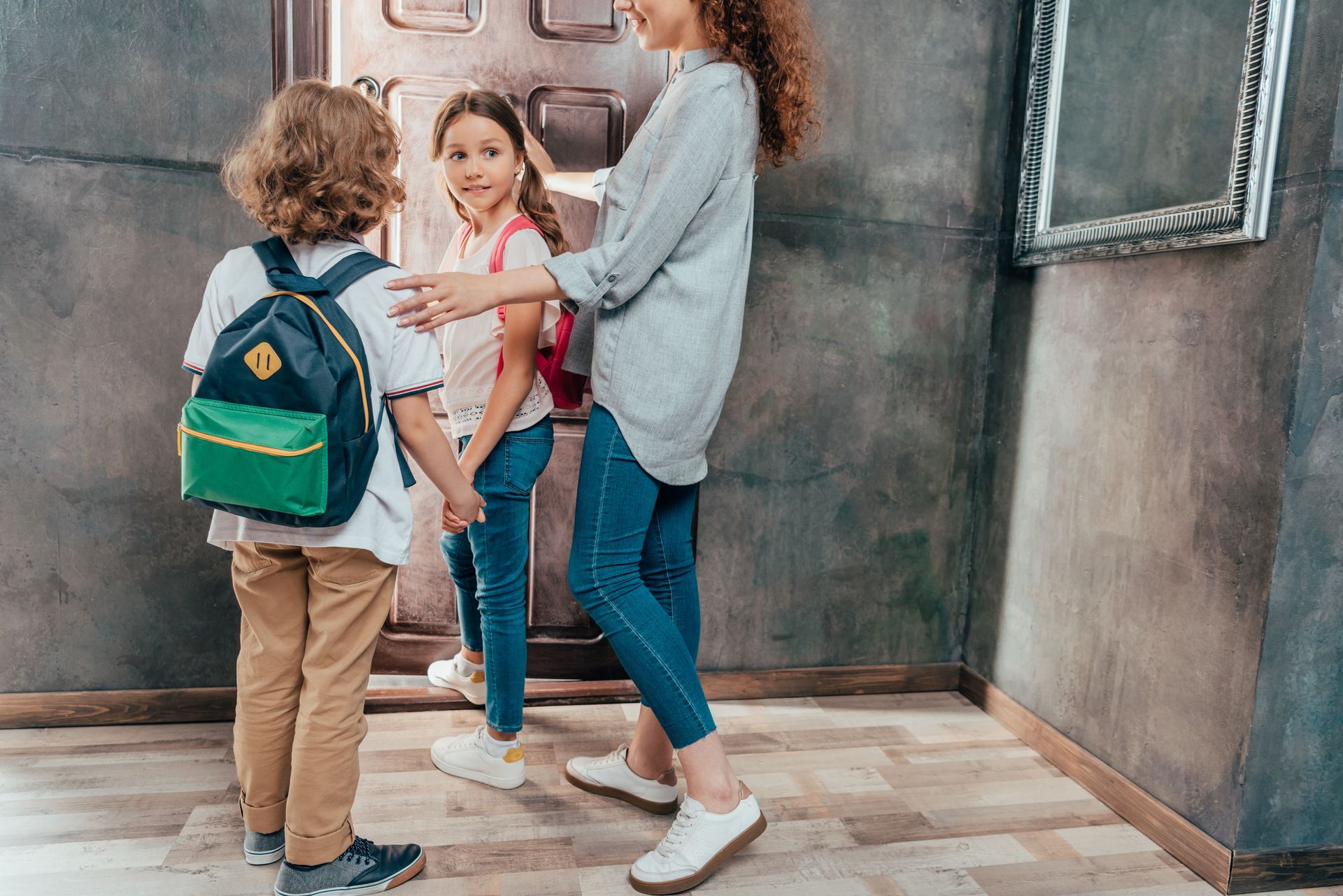 A mother preparing her children for school transportation pickup.