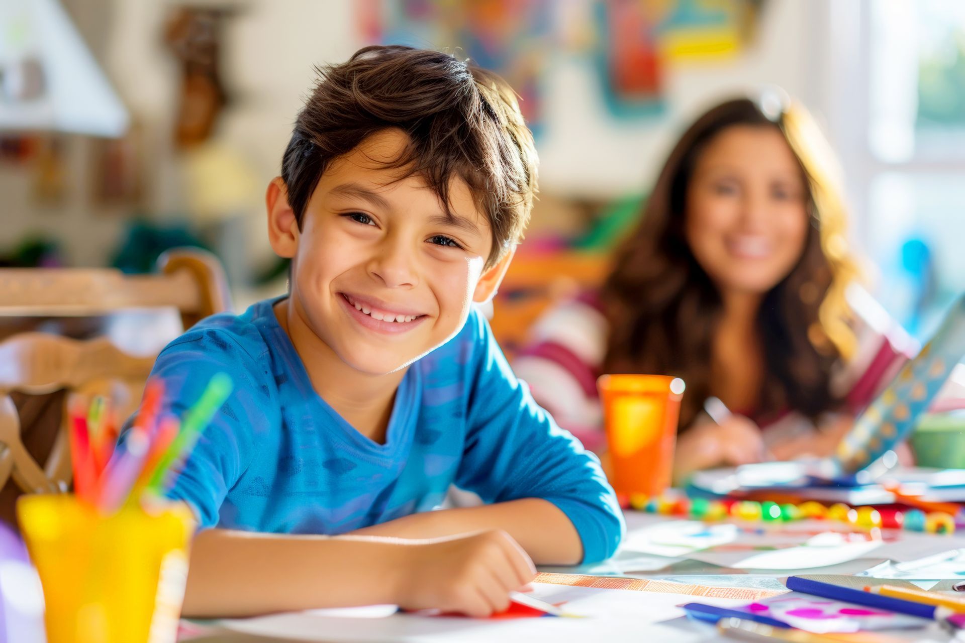 Smiling boy drawing with pencils during homework club activity in a bright classroom.