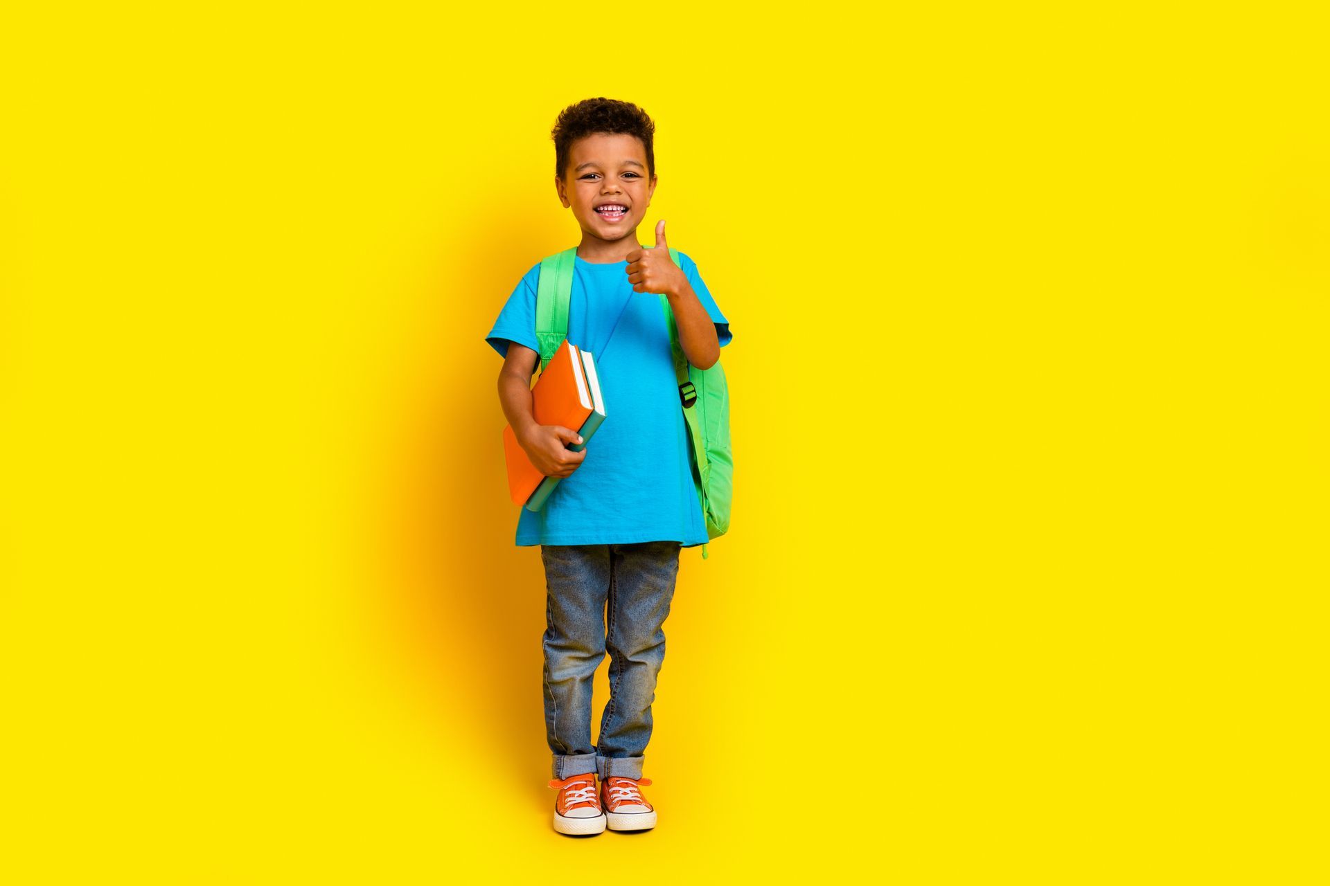 Child with backpack and books giving thumbs up on yellow background. Child with backpack and books giving thumbs up on yellow background.