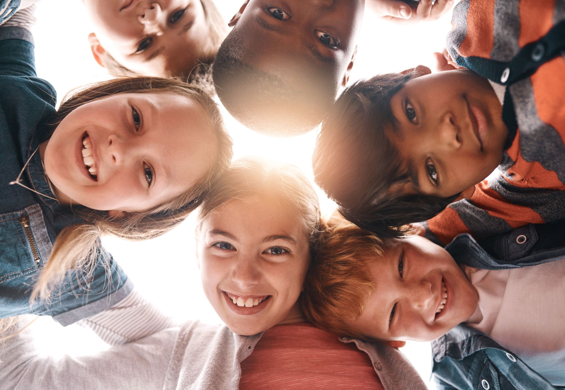 Children in a circle smiling and looking down at the camera. Children in a circle smiling and looking down at the camera.