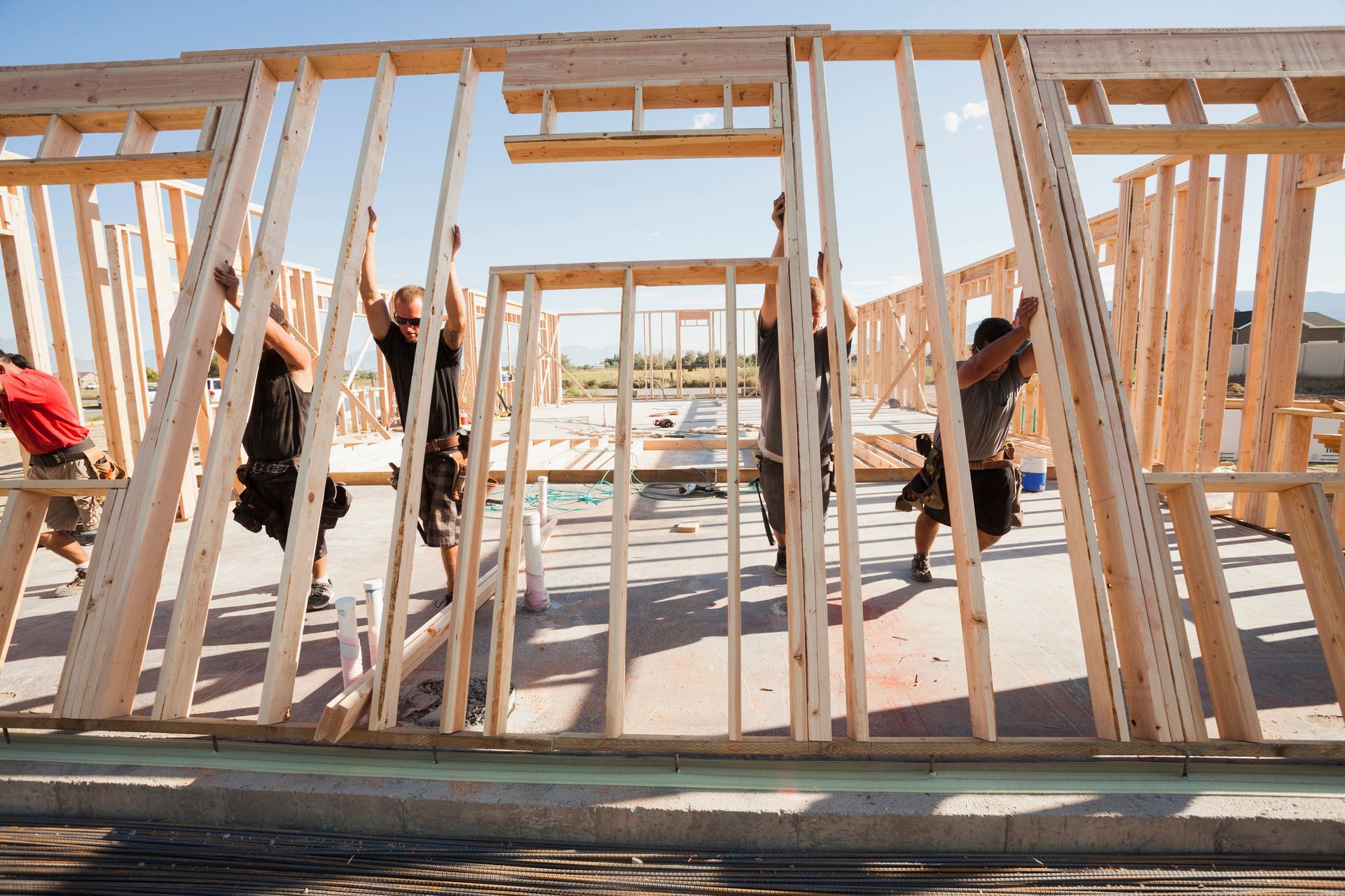 Workers are lifting the wall frame on the construction site.