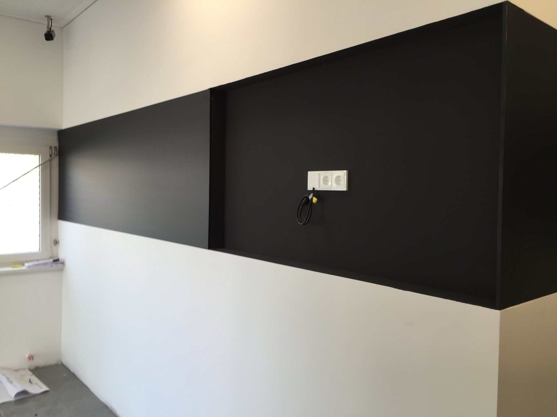 Schwarz-weiß gestrichene Betonwand mit Steckdose