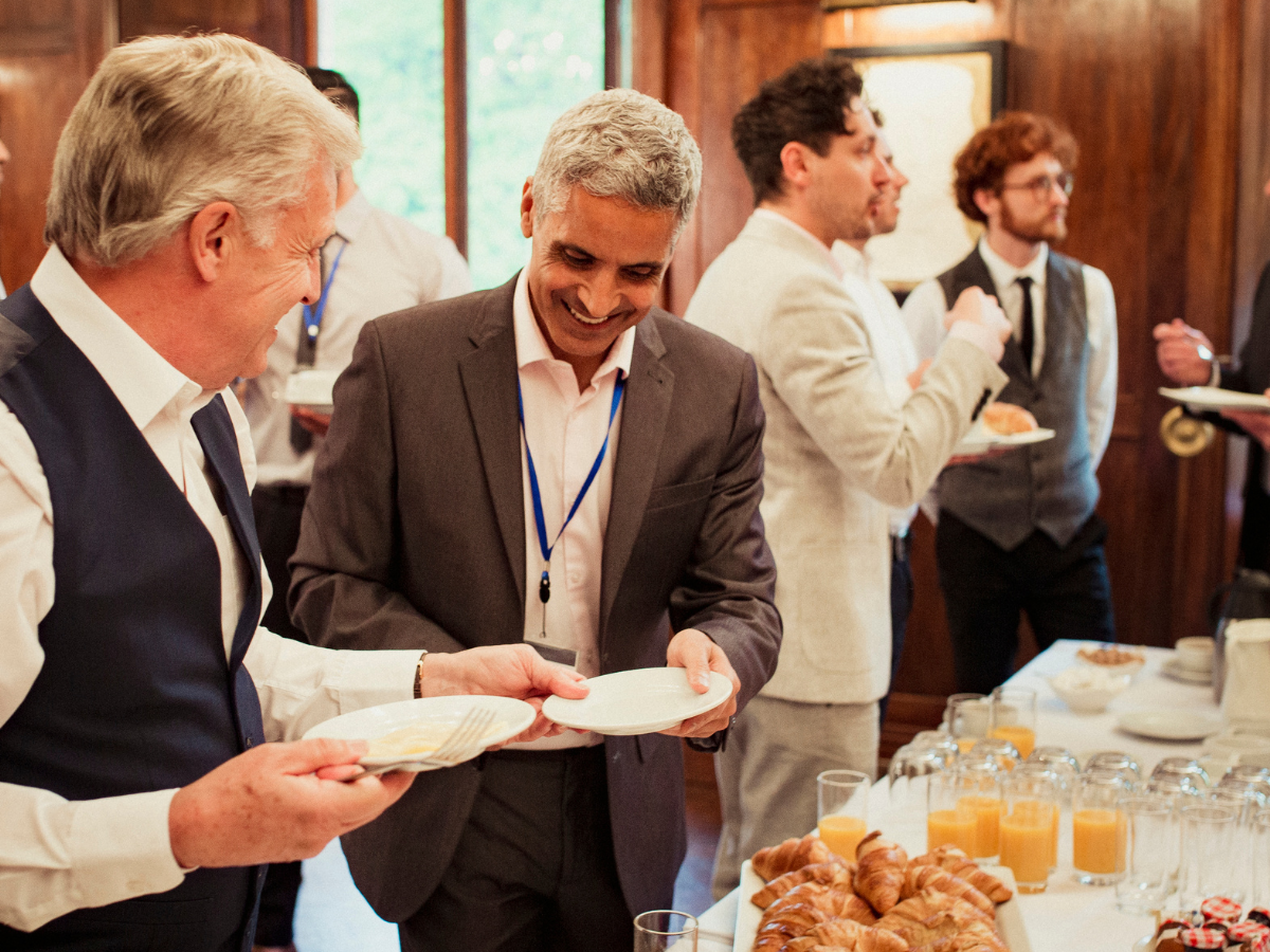 A group of men are standing around a table with food on it