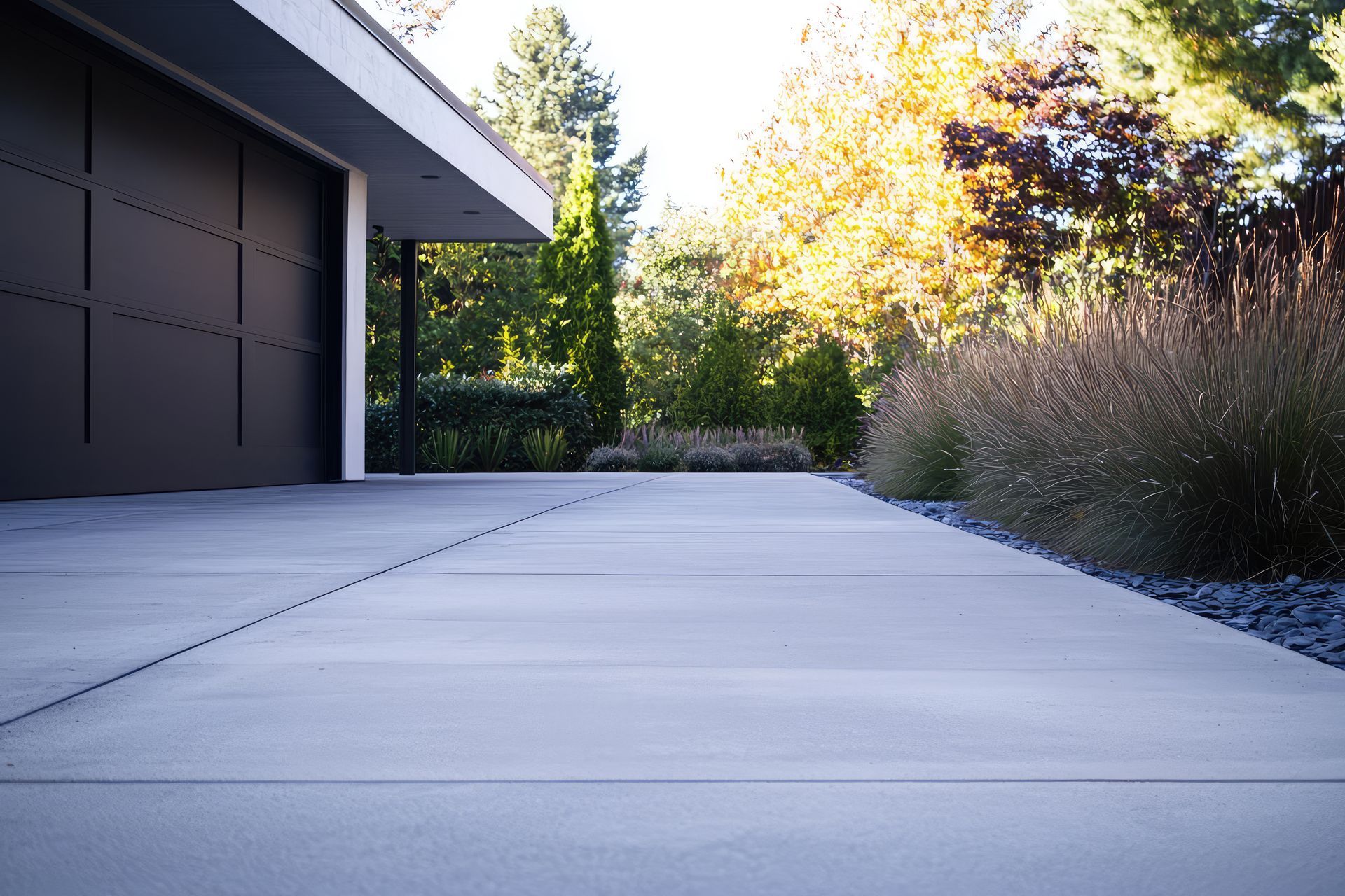 A concrete driveway leading to a garage with trees in the background