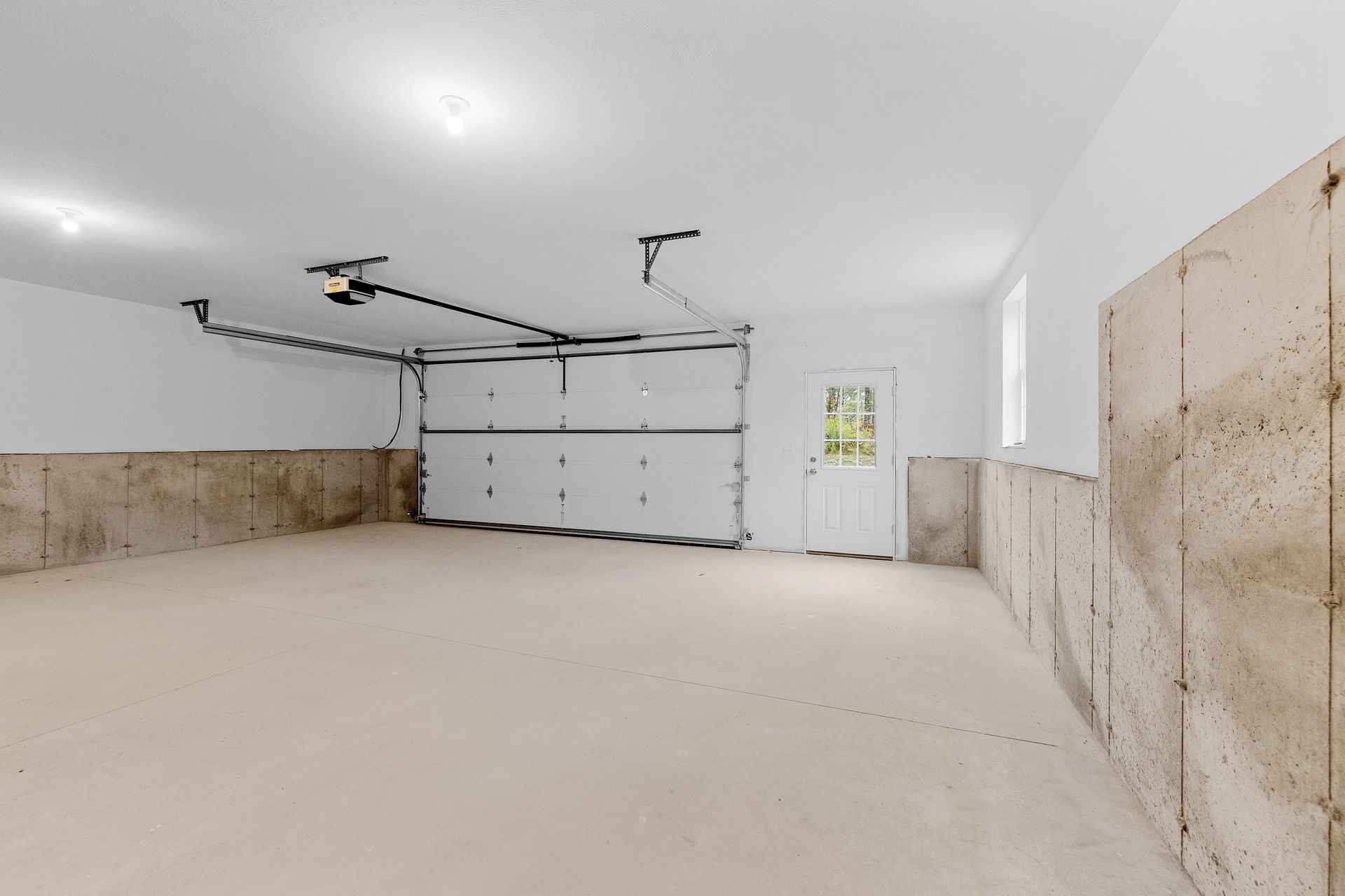 An empty garage with a garage door open and a window.