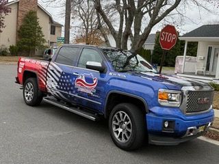 Roofers working on a beige house's roof, partial roof exposed, ladder present, clear blue sky.