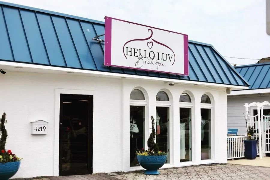 Hello Luv Boutique storefront with a pink sign and blue roof.