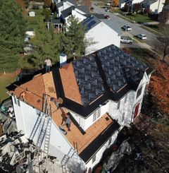 Aerial view of a commercial building with a white roof and multiple HVAC units; parking lot in the foreground.