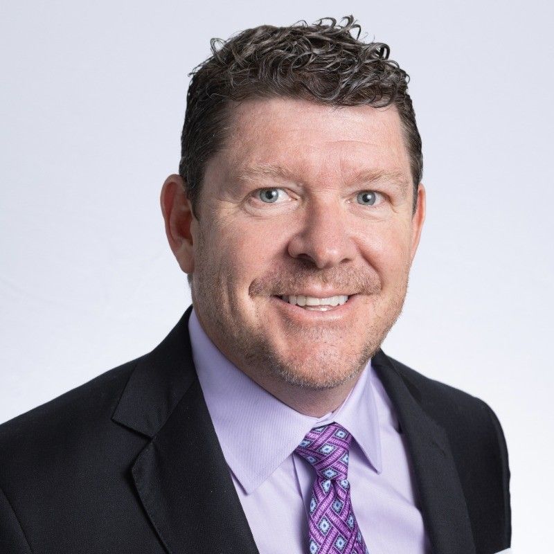 A man and a woman are sitting on a dock overlooking a lake.