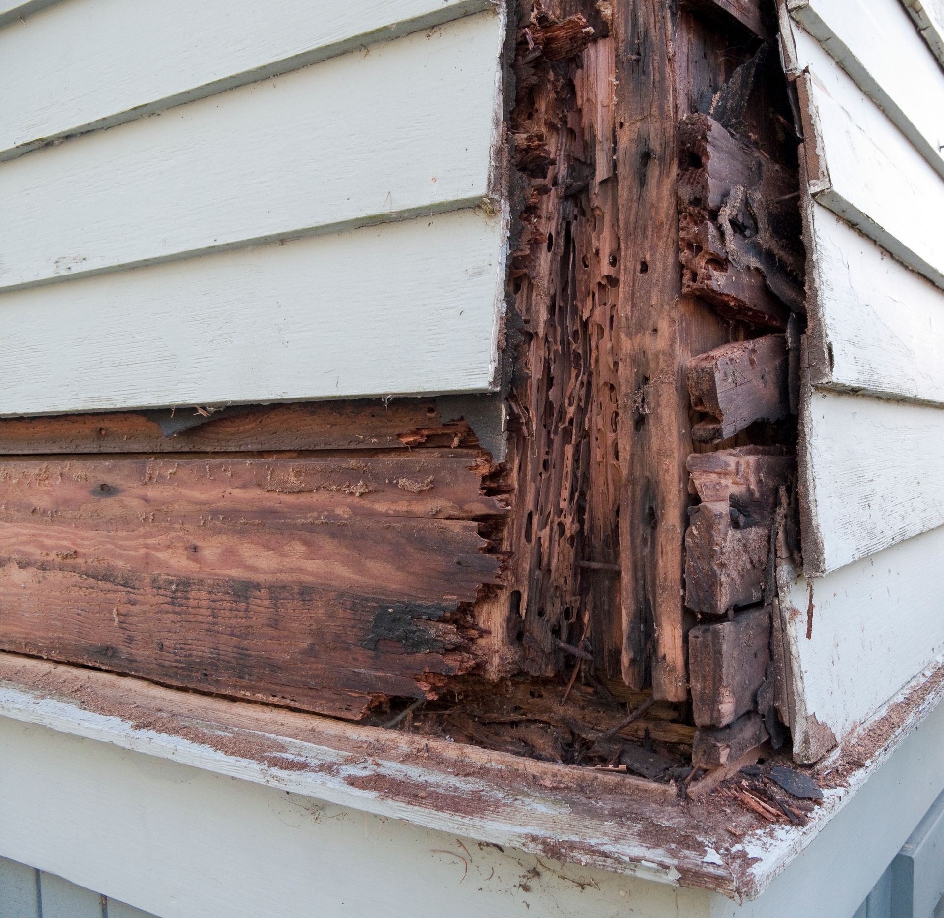 A corner of a house with a lot of wood missing