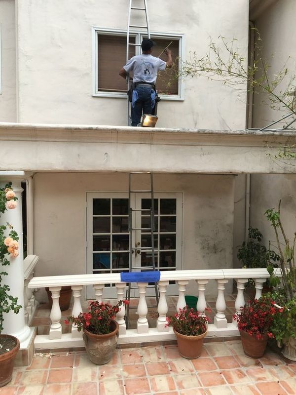 A man on a ladder cleaning a window on the side of a building